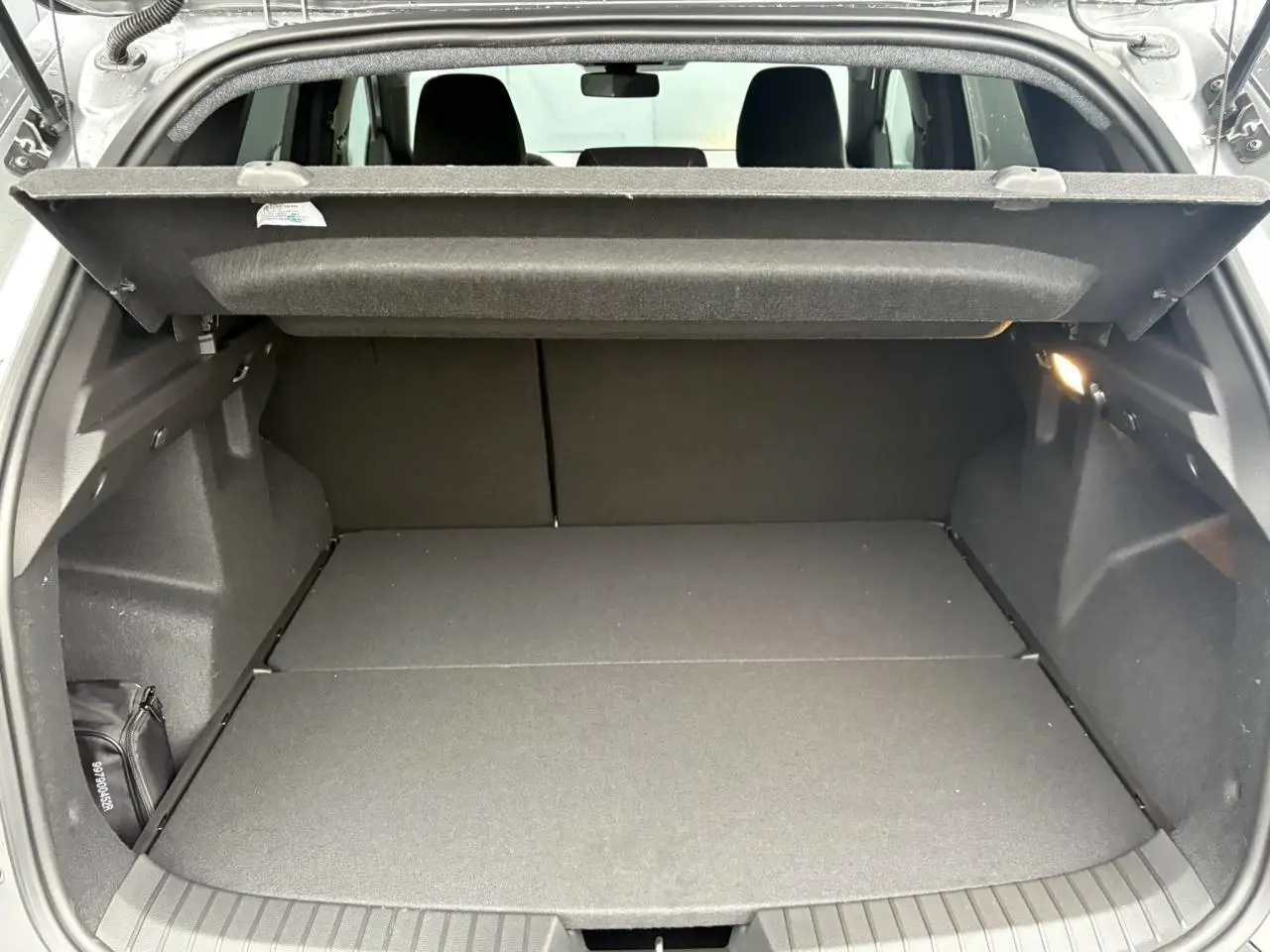 Coffre ouvert du Dacia Duster gris schiste, vue arrière montrant l'espace de chargement avec tablette de séparation.