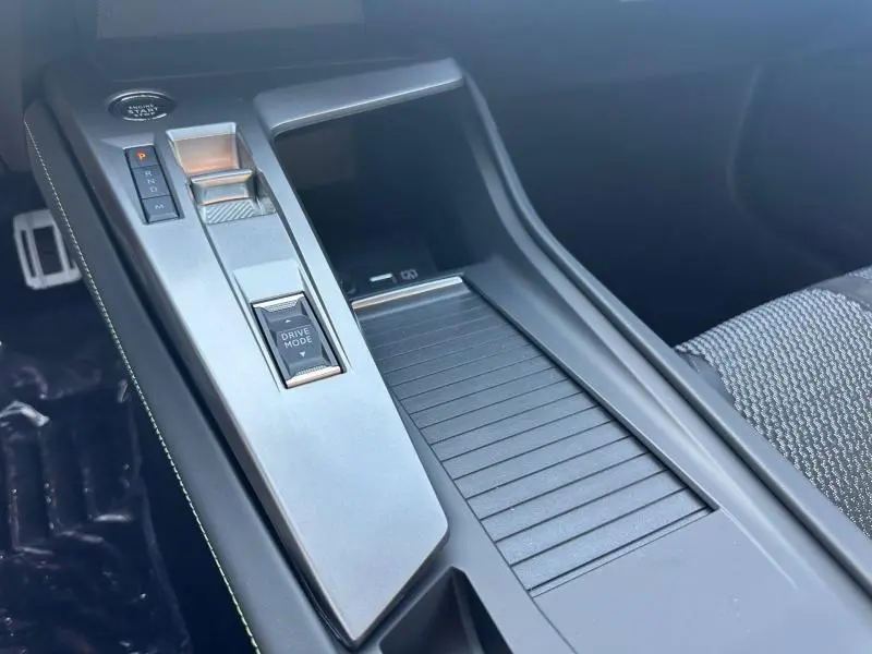 Gros plan sur la console centrale grise de la Peugeot 308 1.5 BlueHDi 130ch avec commandes de boîte auto et rangement coulissant.