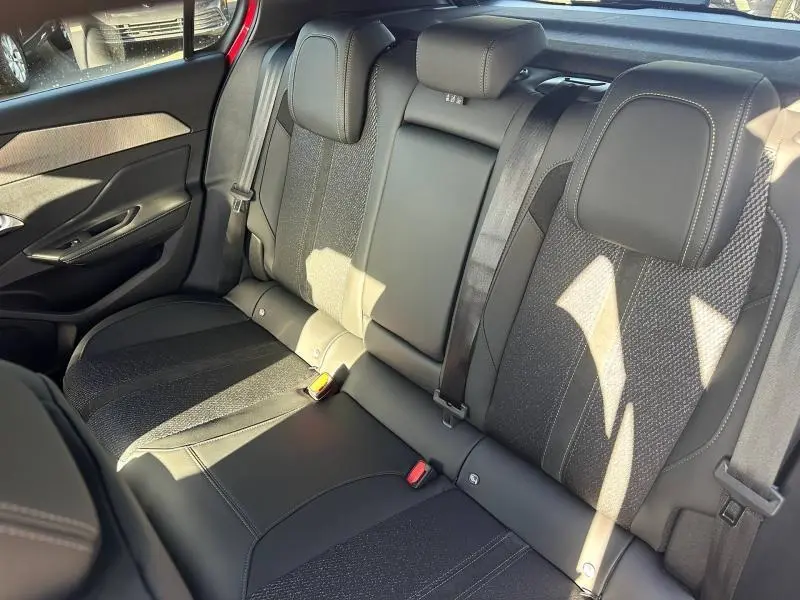 Vue intérieure arrière de la banquette noire bi-matière de la Peugeot 308 2025 avec appuie-têtes et ceintures visibles.