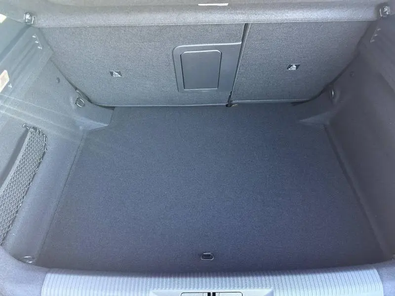 Vue intérieure du coffre spacieux et propre de la Peugeot 308, avec revêtement gris foncé et filet latéral de rangement.