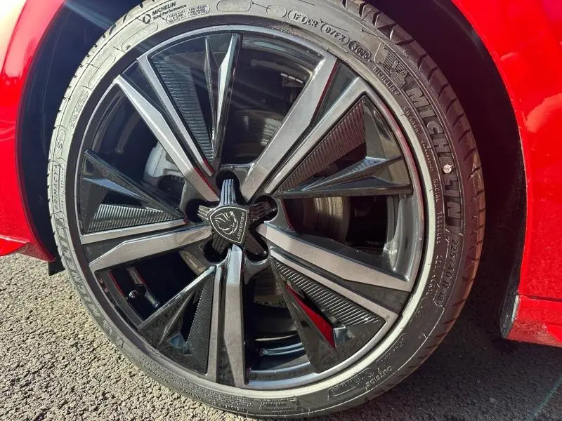 Gros plan sur la jante alu noire et grise de la Peugeot 308 rouge Elixir, avec pneu Michelin visible.