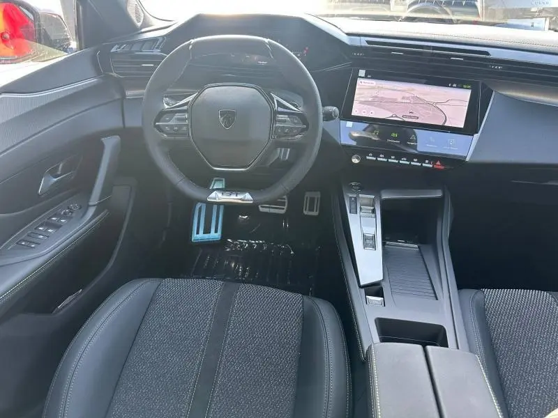 Vue intérieure avant du Peugeot 308 rouge Elixir, avec volant compact, écran tactile et pédalier sport en aluminium.