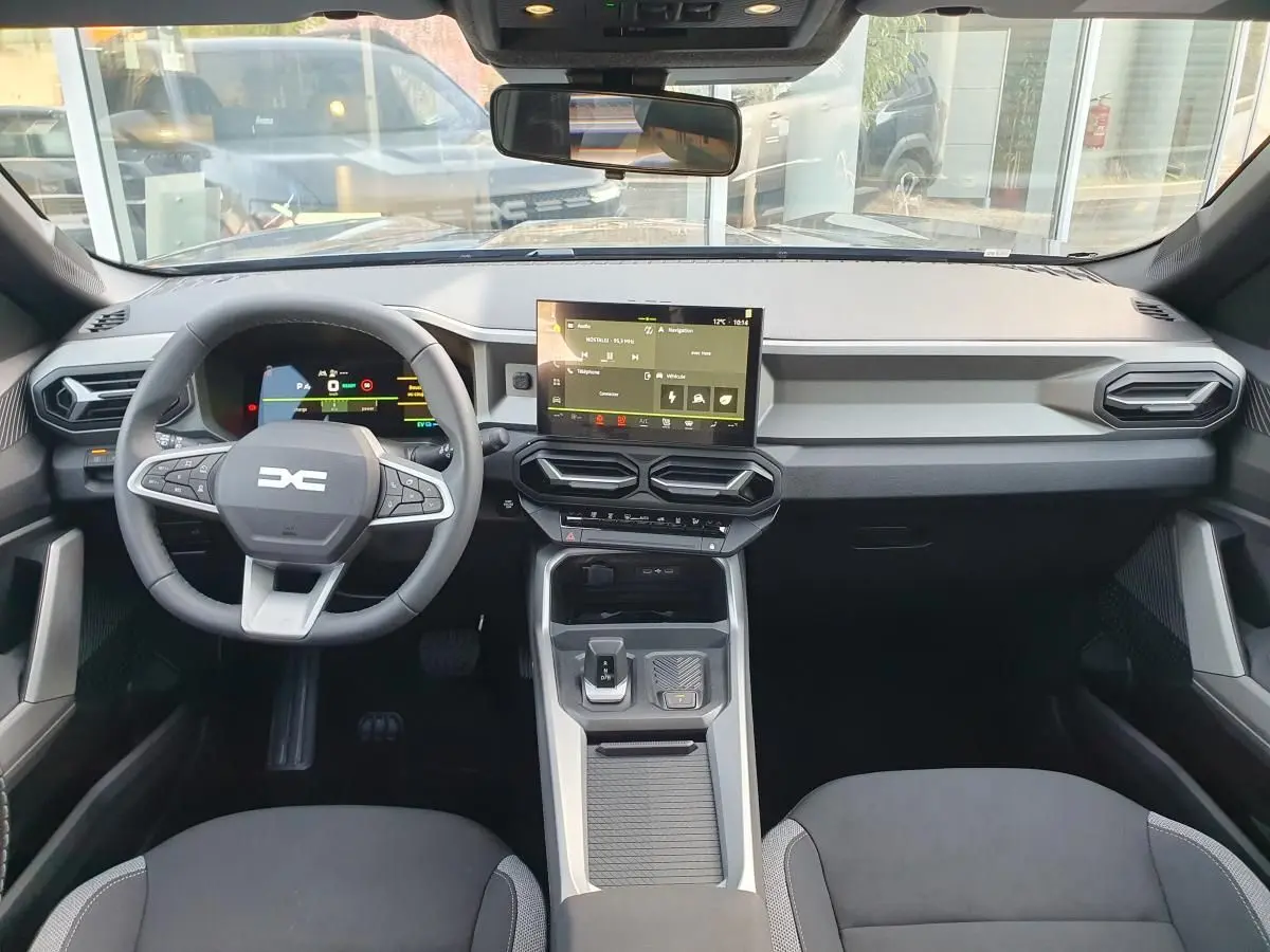 Vue intérieure avant du tableau de bord du Dacia Bigster gris schiste avec écran tactile central et volant multifonction.