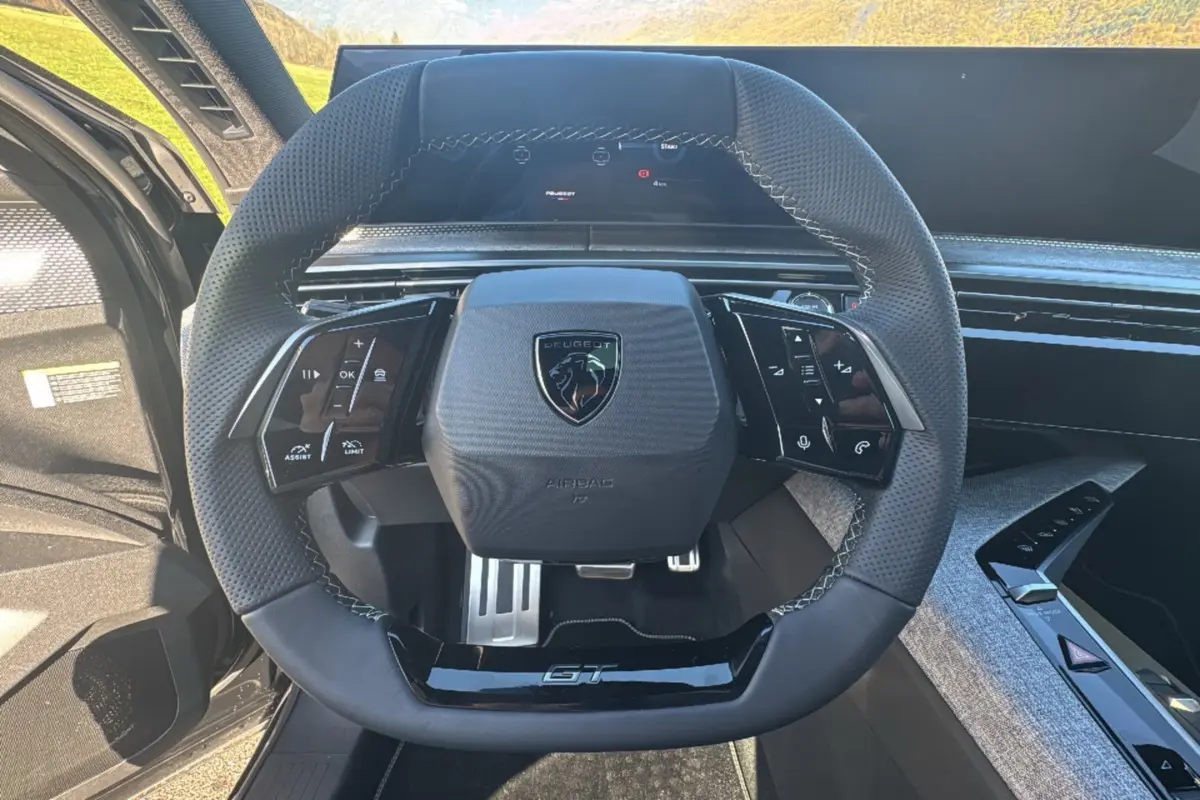 Vue rapprochée du volant cuir multifonctions Peugeot 3008 GT noir avec logo et pédalier aluminium visible.