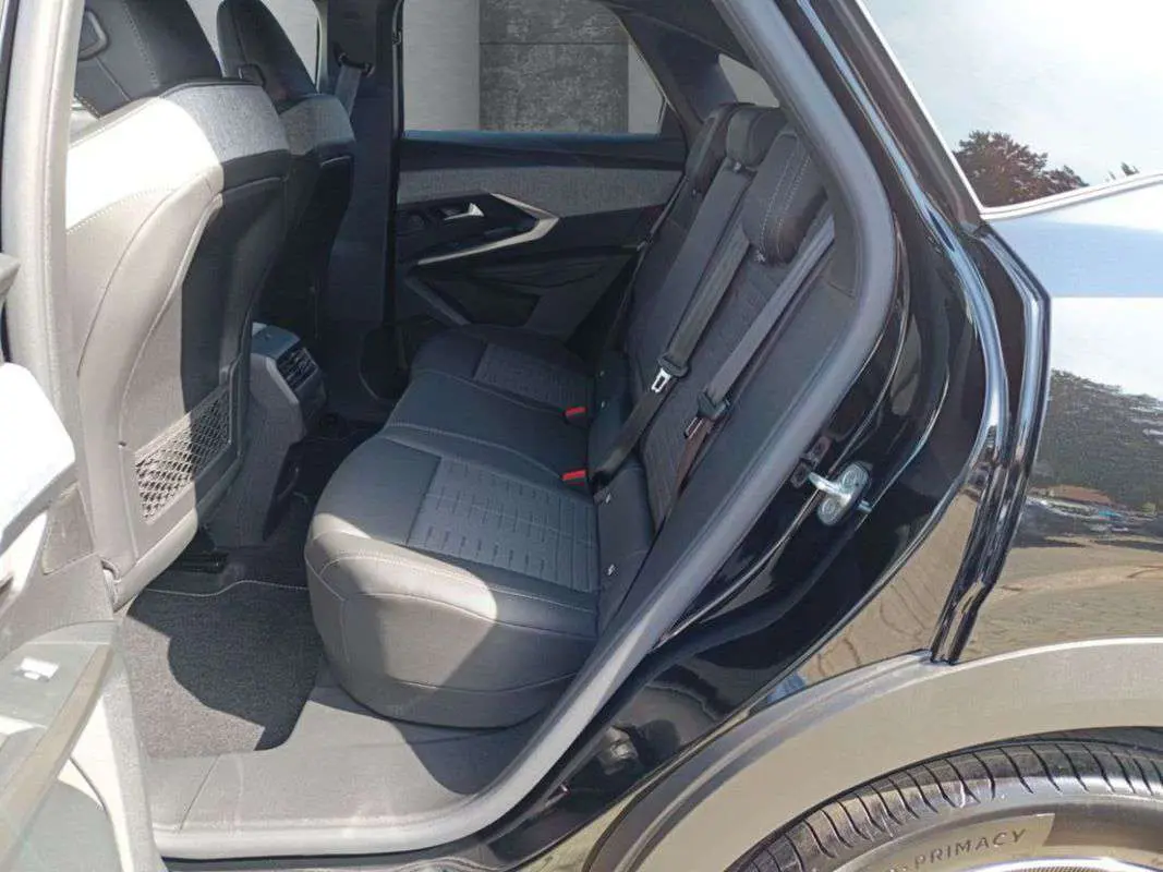Vue côté gauche arrière du Peugeot 3008 New Hybrid 145 GT 360 noir perla nera, montrant la banquette arrière en tissu et cuir.