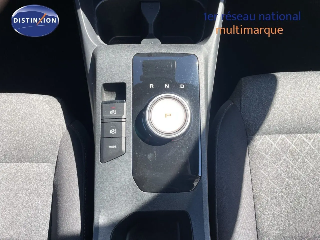 Vue plongeante sur la console centrale de la MG3 2025, avec molette de boîte auto et sièges tissu gris.