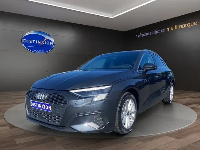 Audi A3 Sportback gris Manhattan en 3/4 avant droit, avec phares à matrice LED et vitres arrière surteintées.