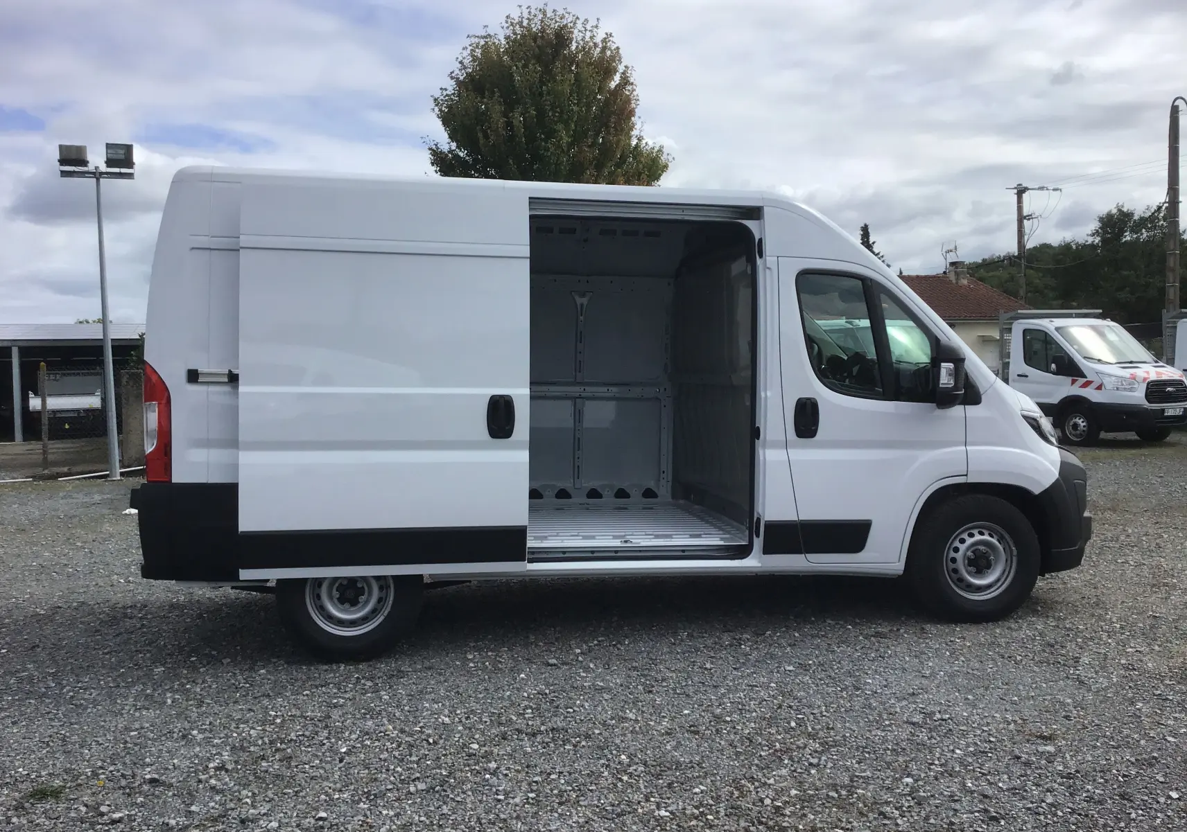 Vue latérale droite d'un Peugeot Boxer blanc 2025 avec porte coulissante ouverte montrant l'espace de chargement vide.