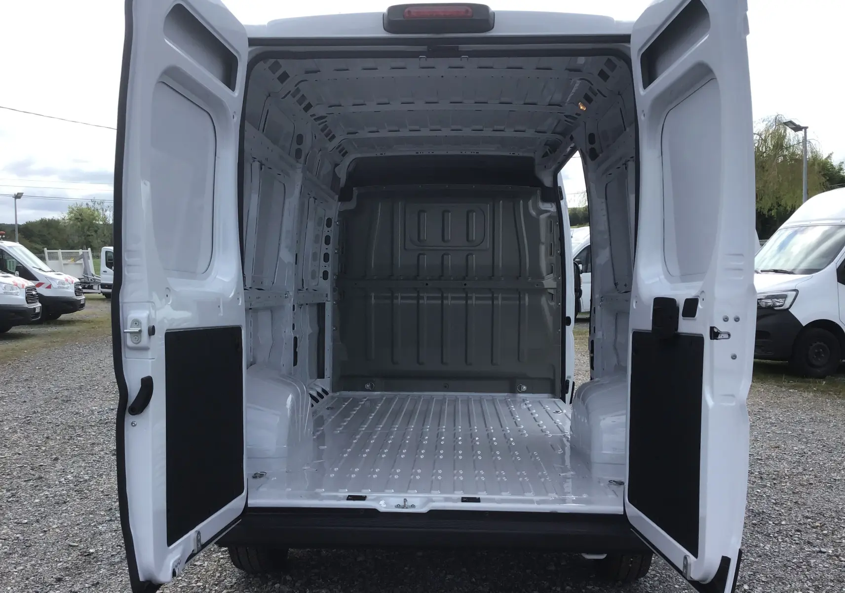 Vue arrière du Peugeot Boxer Fourgon blanc 2025 avec portes ouvertes montrant l'espace de chargement vide et métallique.