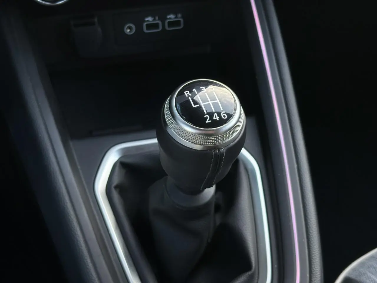 Gros plan sur le levier de vitesses manuel noir de la Renault Clio V TCe 90 Techno, entouré de garniture argentée.