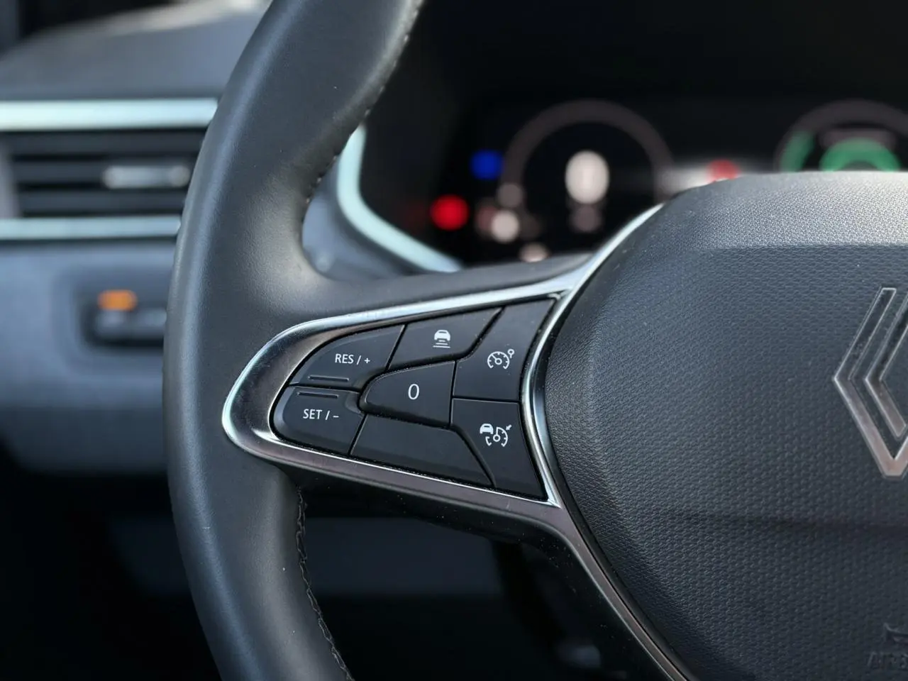 Gros plan sur le volant multifonction noir de la Renault Clio 2025 avec commandes de régulateur de vitesse.