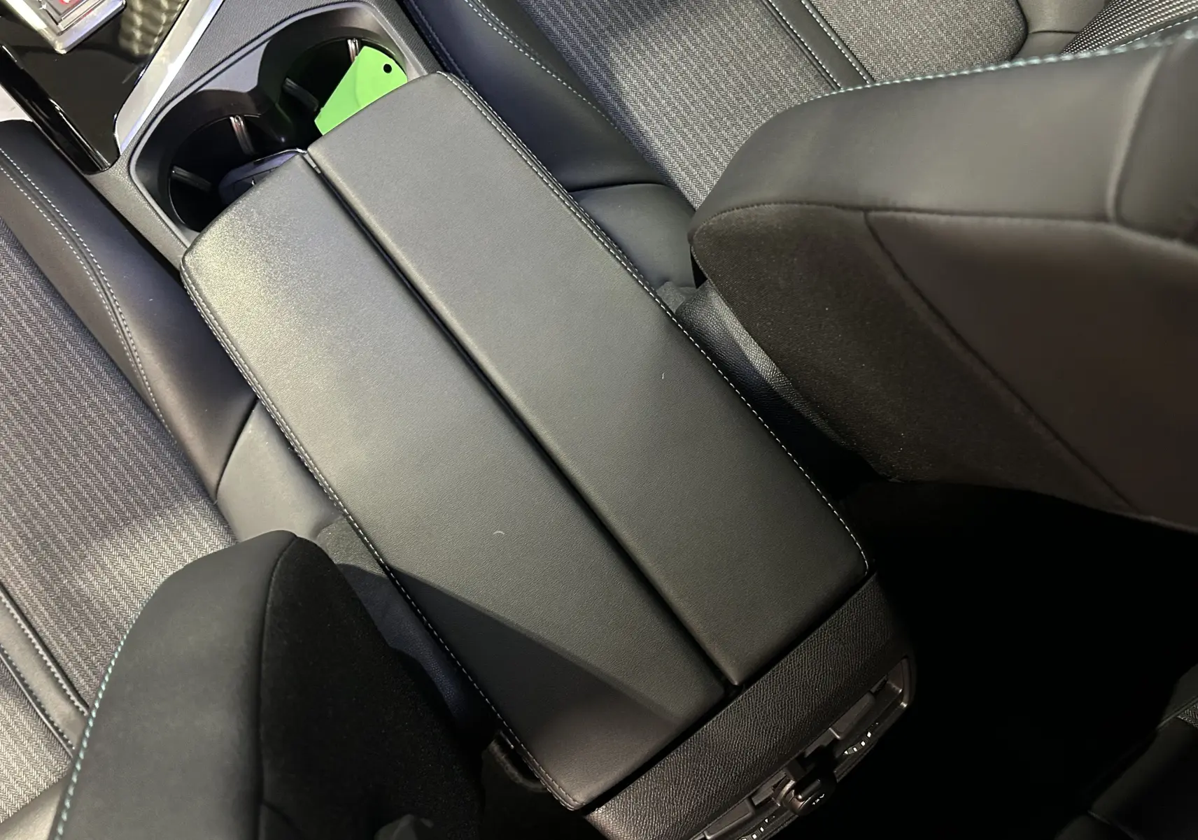 Vue plongeante sur l'accoudoir central noir et les sièges en tissu gris du Peugeot 3008 Puretech 130 EAT8 Allure 2022.