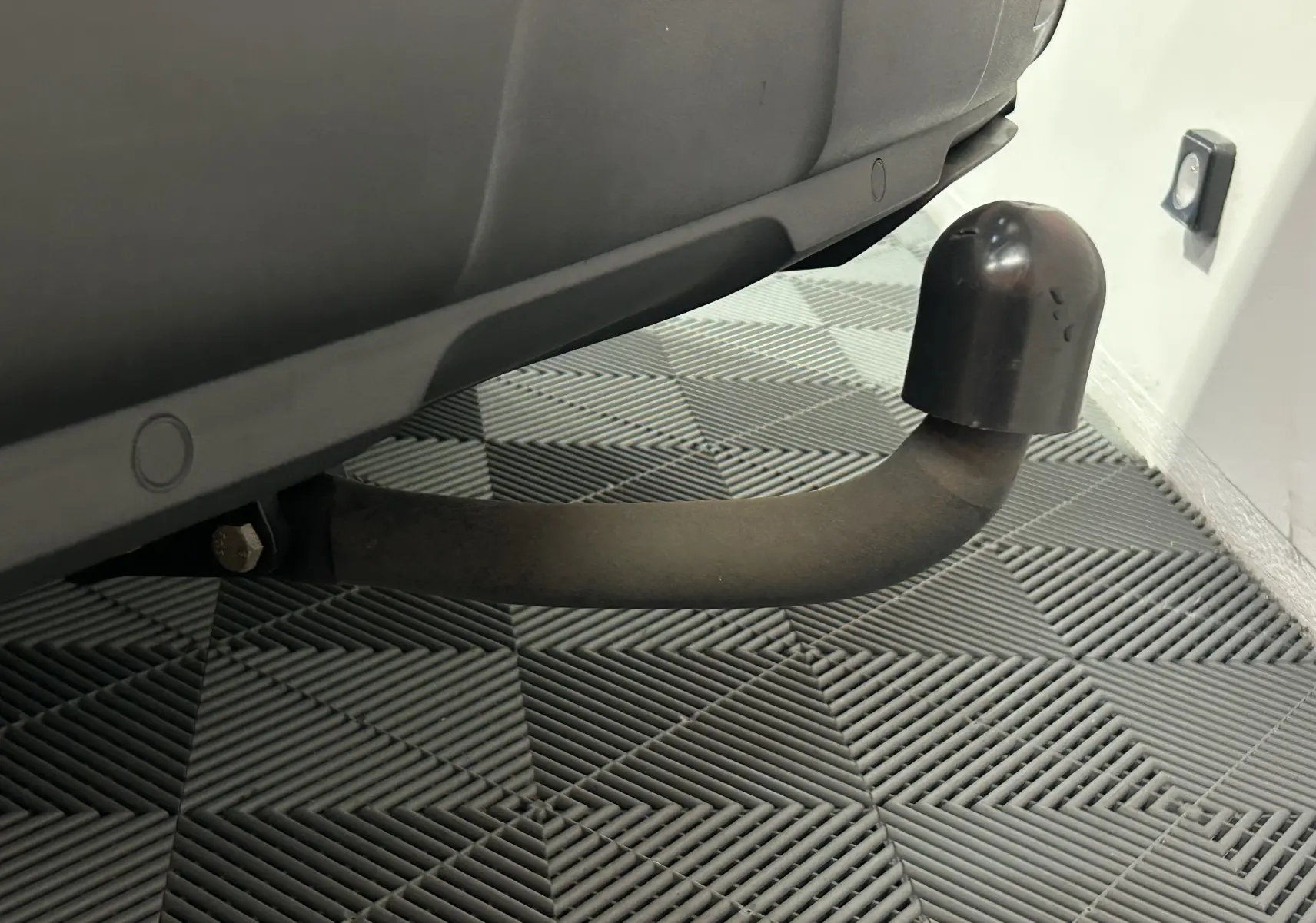 Gros plan sur l'attelage noir sous la partie arrière d'un Peugeot 3008 gris Artense avec toit noir.