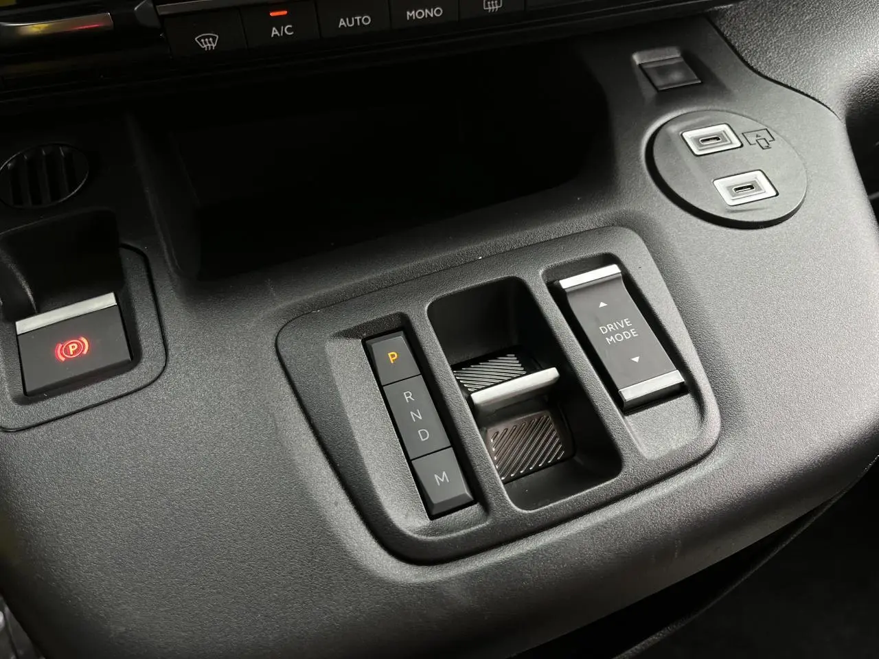 Gros plan sur la console centrale noire du Citroën Berlingo Multispace 2025, avec commandes de boîte auto et mode de conduite.