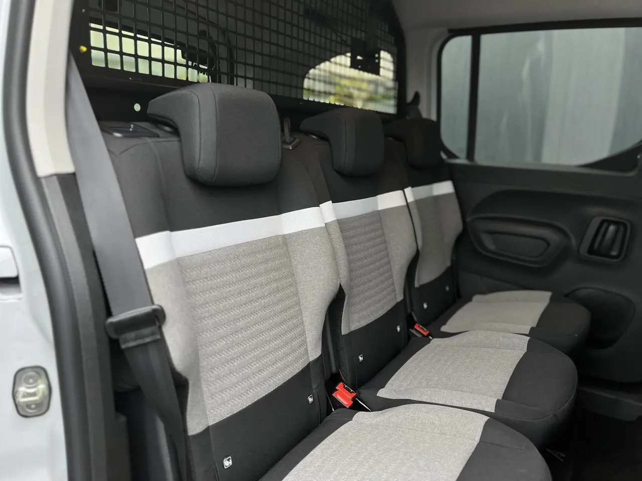 Vue intérieure côté droit des sièges arrière gris et noirs du Citroën Berlingo Multispace blanc glacier avec grille de séparation.