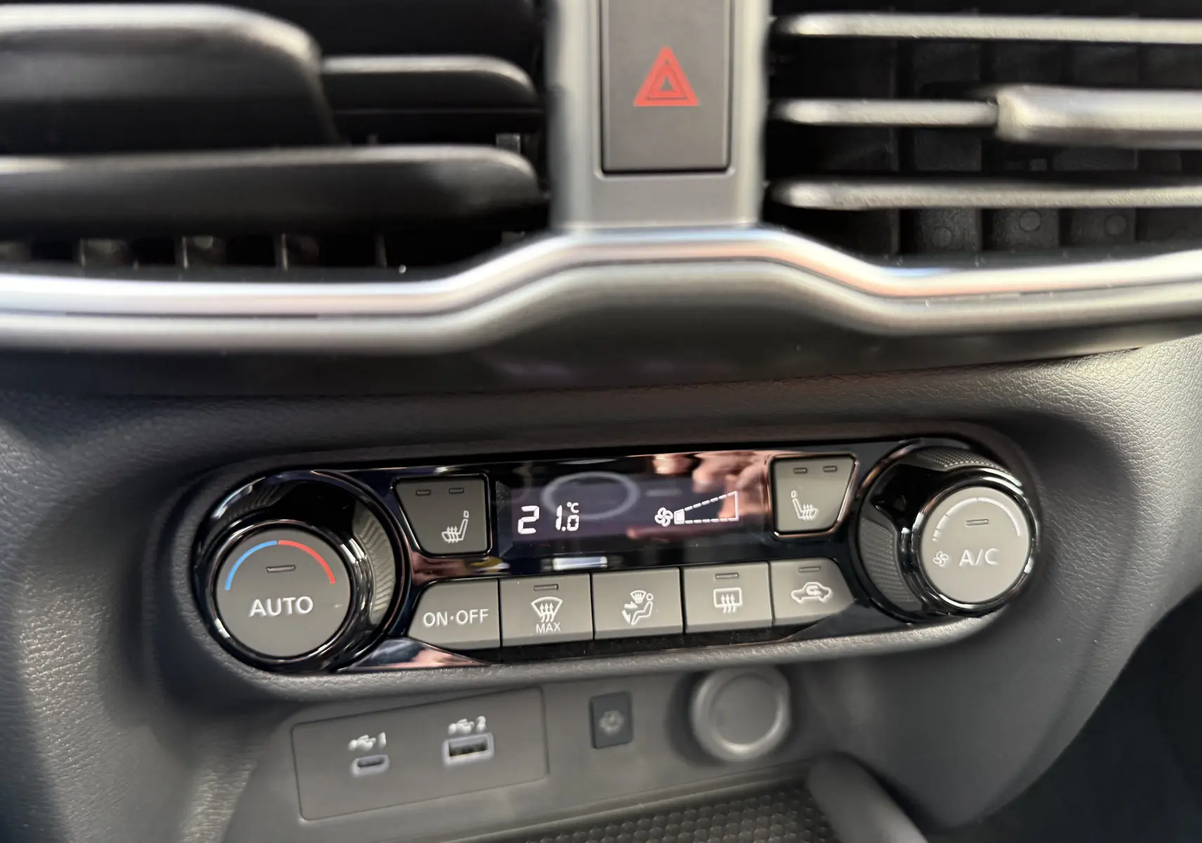 Vue rapprochée de la console centrale du Nissan Juke 2025, montrant les commandes de climatisation et sièges chauffants.