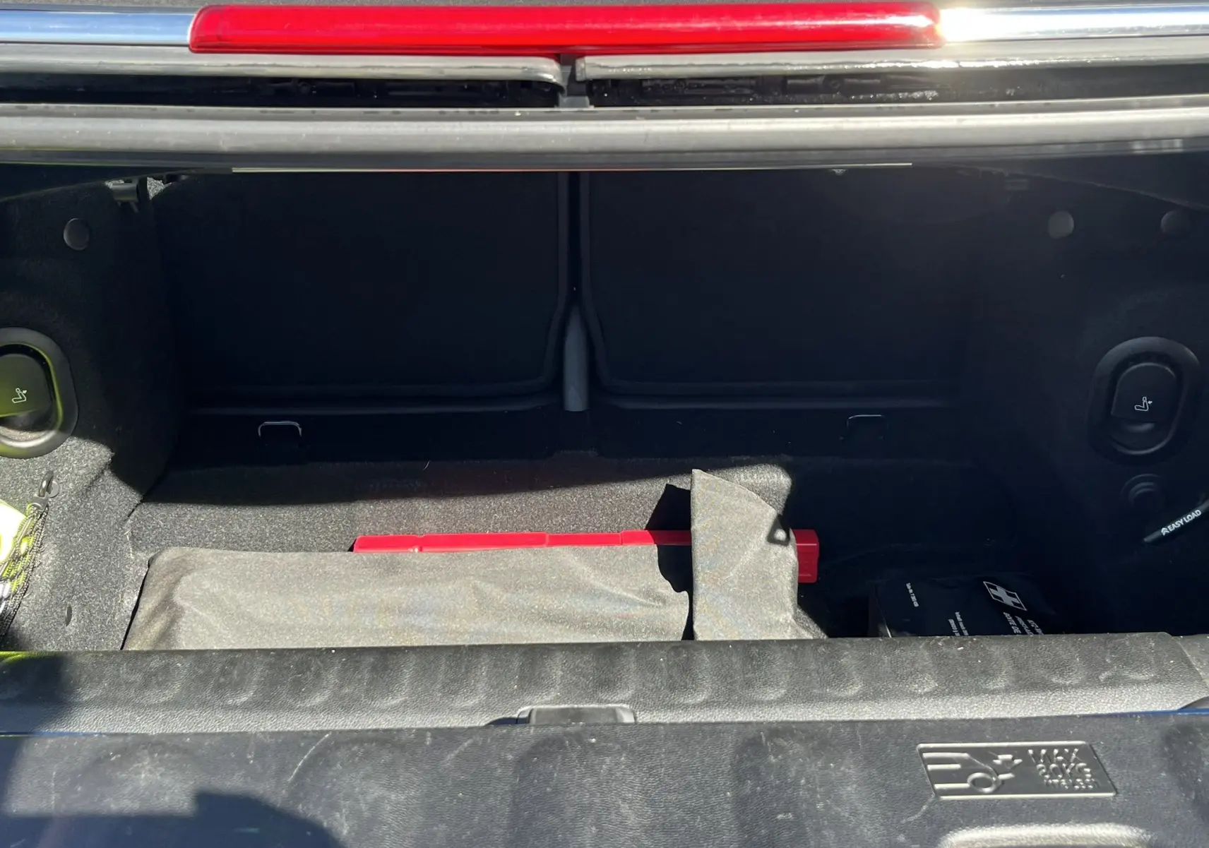 Coffre ouvert d’une MINI Cabriolet F57 Cooper S bleu, vue plongeante sur l’espace de rangement avec accessoires visibles.