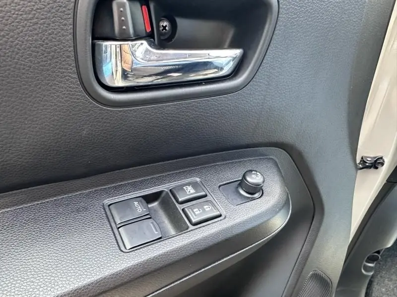 Vue rapprochée de la porte avant gauche beige du Suzuki Ignis 2023, montrant la poignée chrome et les commandes électriques.