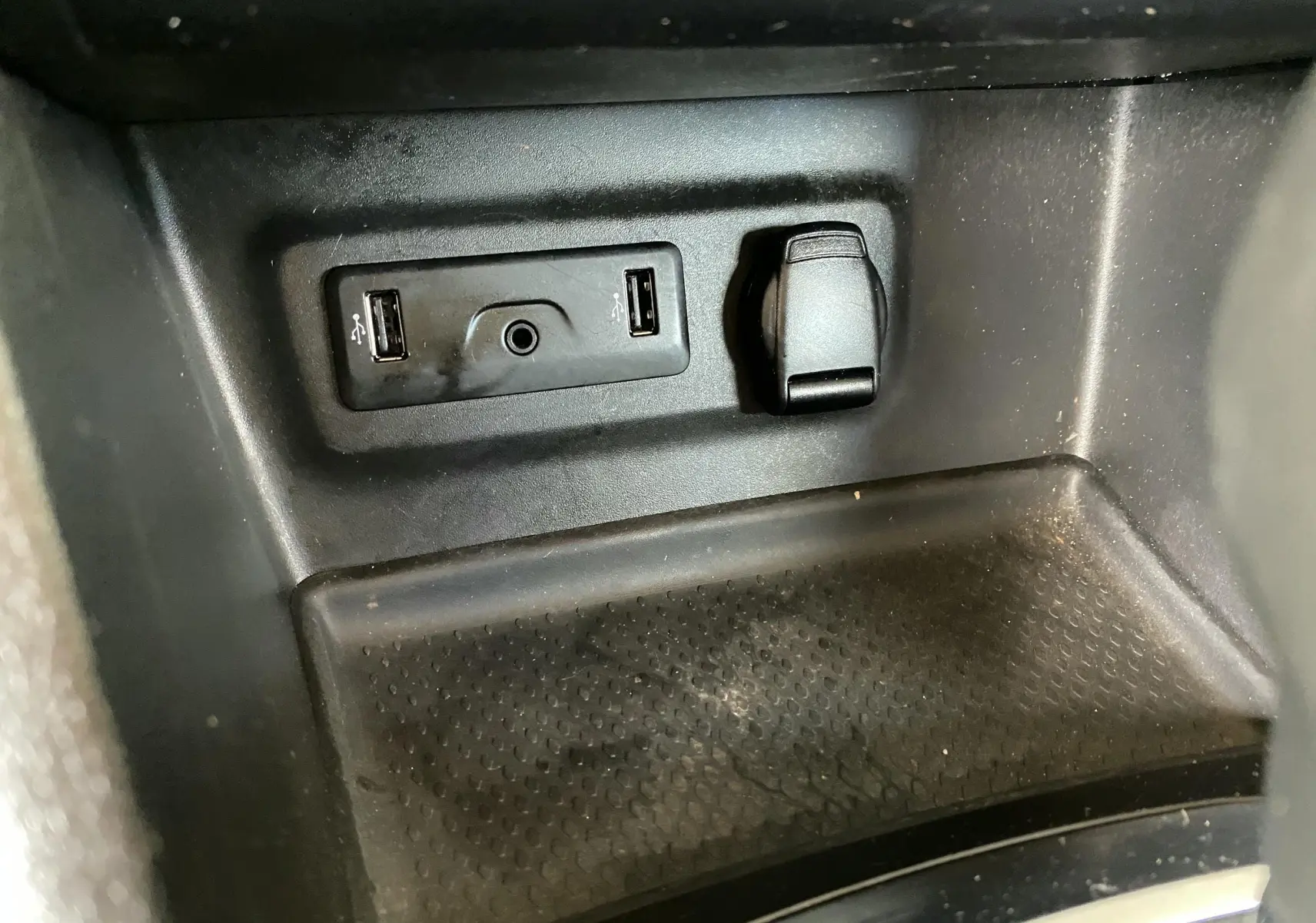 Gros plan sur la prise USB et prise allume-cigare dans l'habitacle noir d'une Renault Mégane IV Berline.