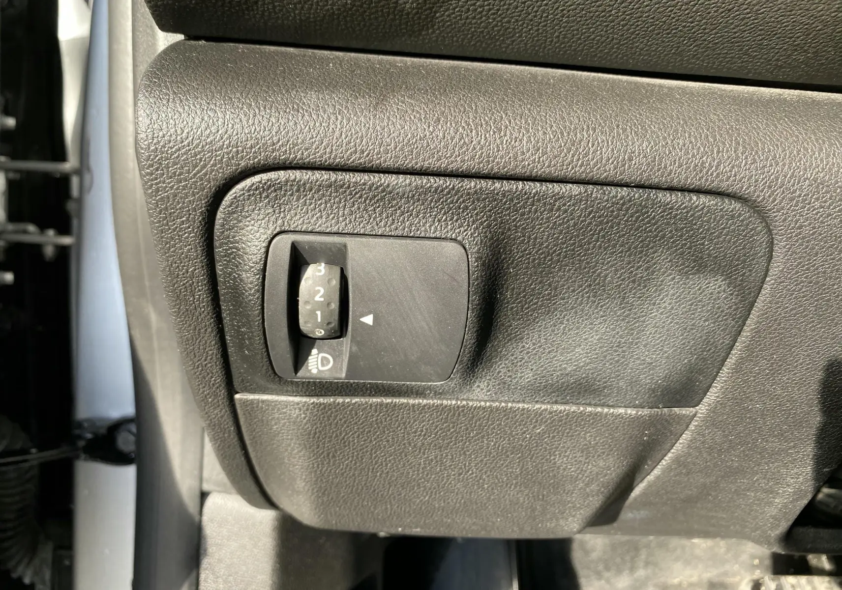 Gros plan sur le réglage d'intensité des phares côté conducteur d'une Renault Mégane IV Berline gris 2020.
