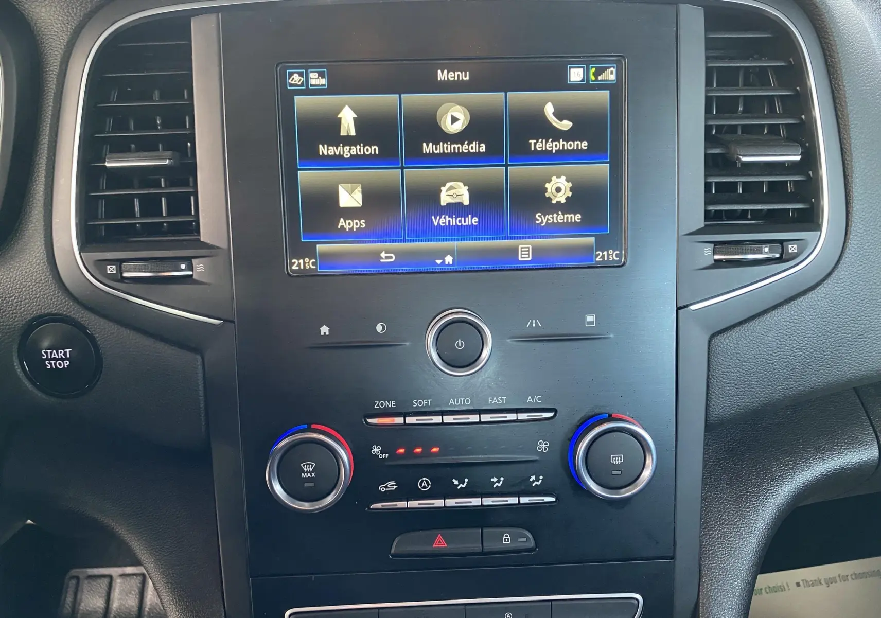 Vue rapprochée du tableau de bord noir de la Renault Mégane IV Berline avec écran tactile et commandes climatisation.