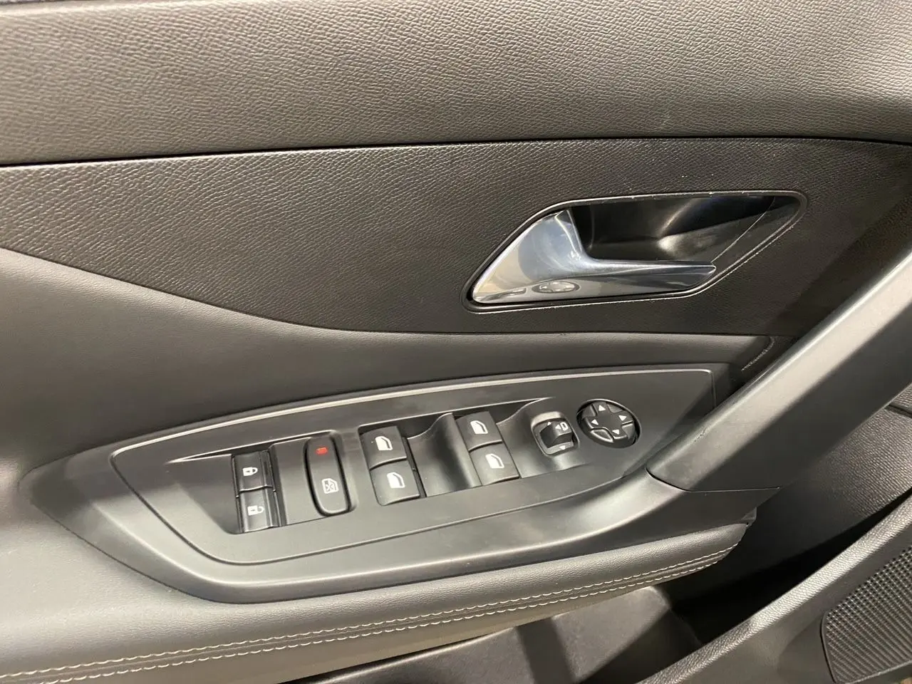 Gros plan sur la commande des vitres et la poignée intérieure côté gauche d'une Peugeot 308 noire Perla Nera 2024.