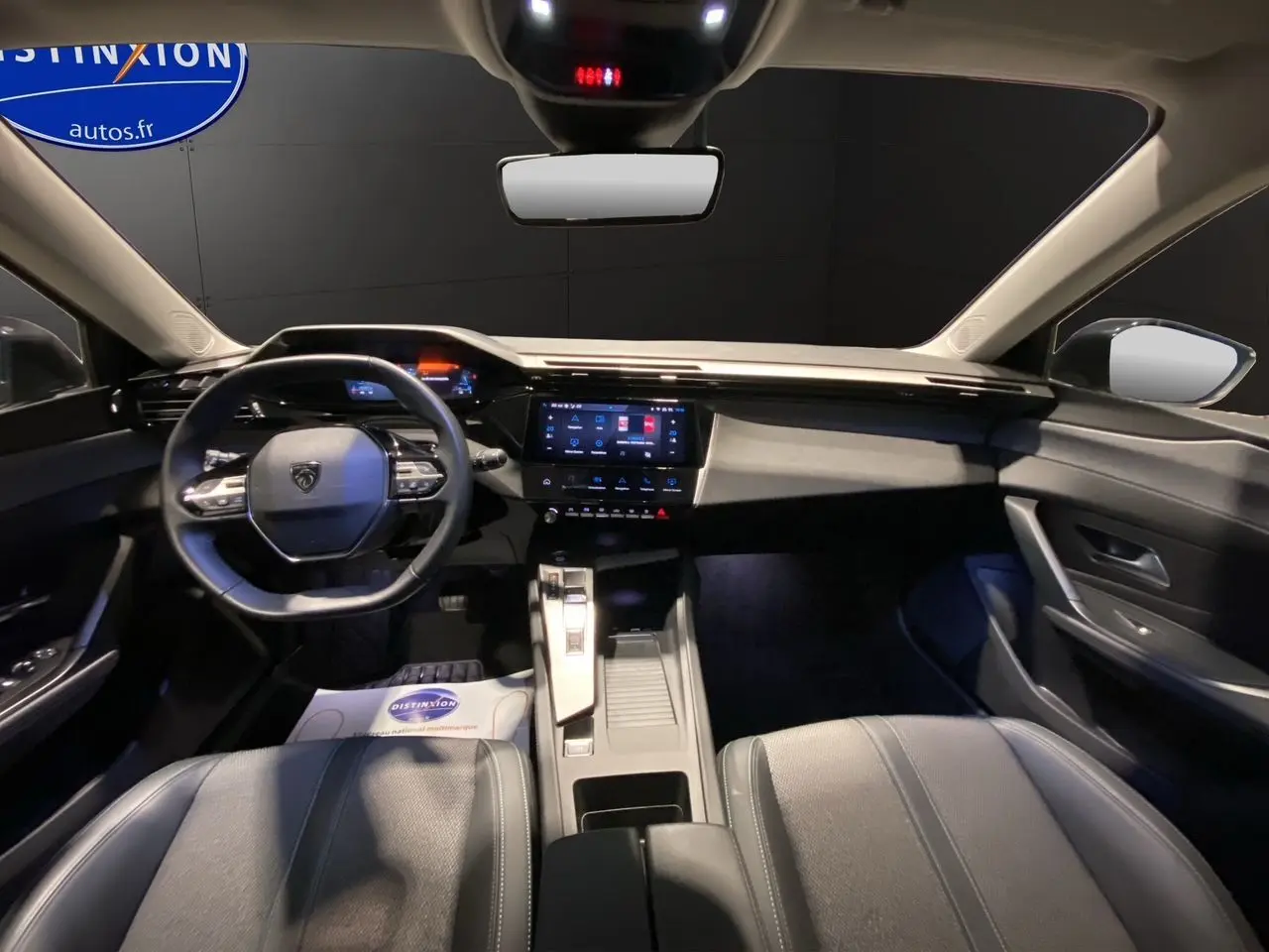 Intérieur noir de la Peugeot 308 2024, vue avant centrée sur le tableau de bord et le volant compact multifonctions.