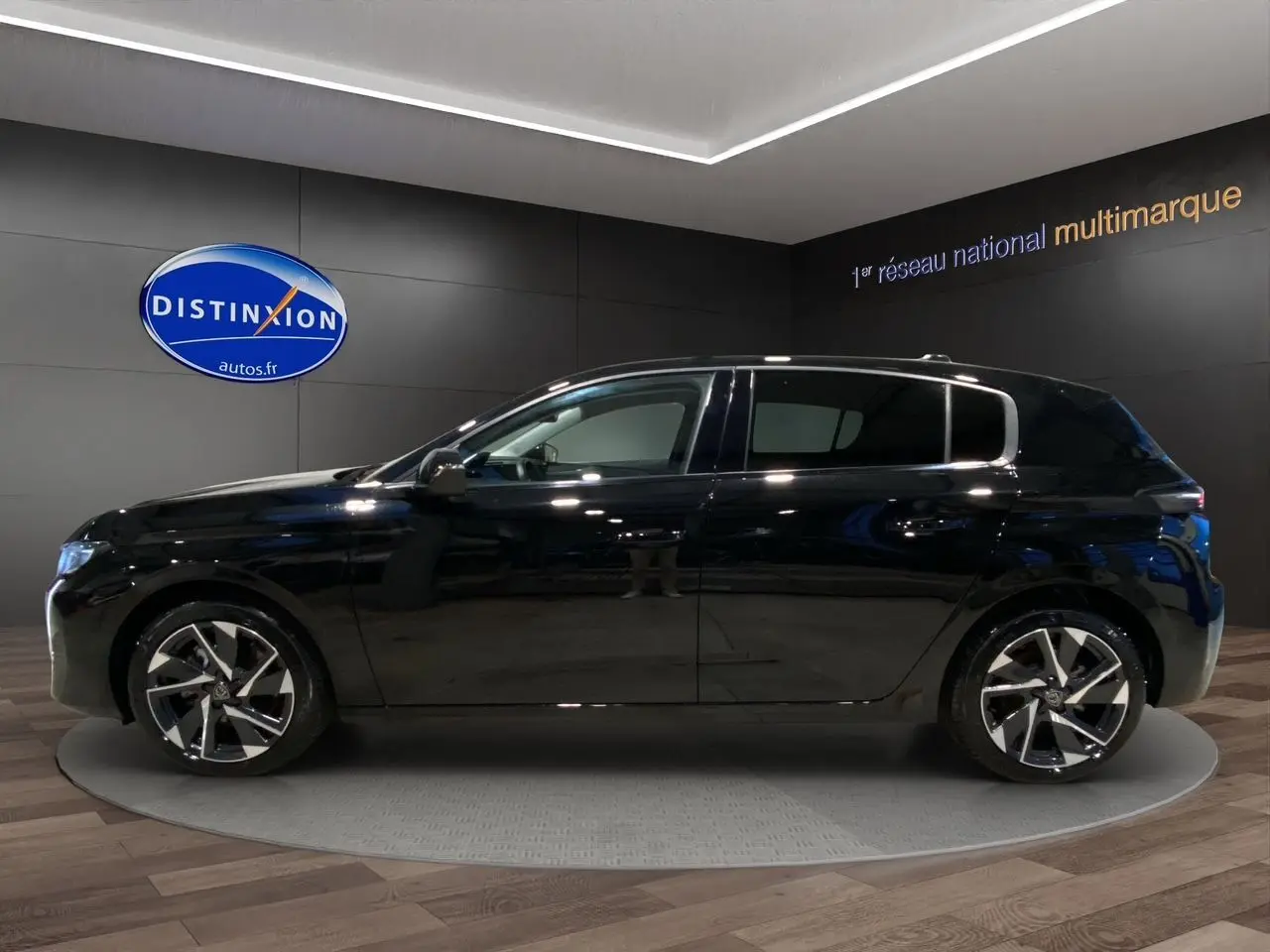 Profil côté gauche de la Peugeot 308 noire Perla Nera 2024, avec jantes alliage et lignes épurées visibles en showroom.