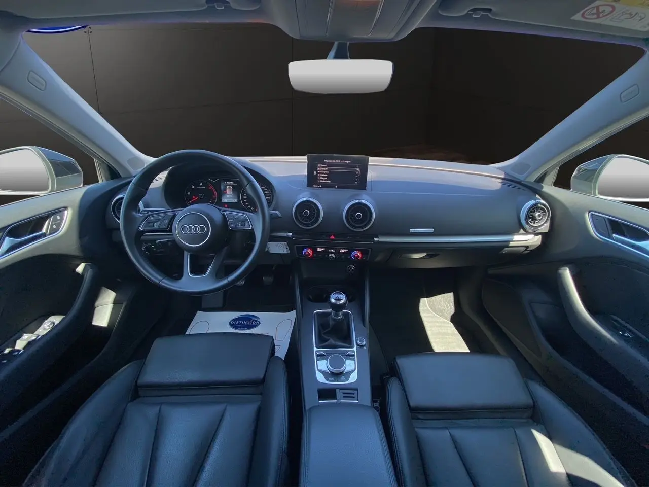 Intérieur noir d'une Audi A3 Sportback 2020, vue frontale du tableau de bord avec volant, écran et sellerie cuir chauffante.