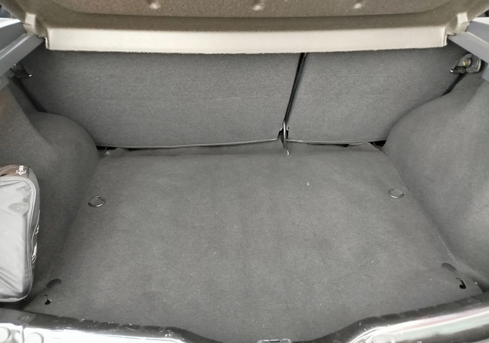 Coffre ouvert de Dacia Sandero noire 2011, vue intérieure montrant un espace de chargement propre et vide.