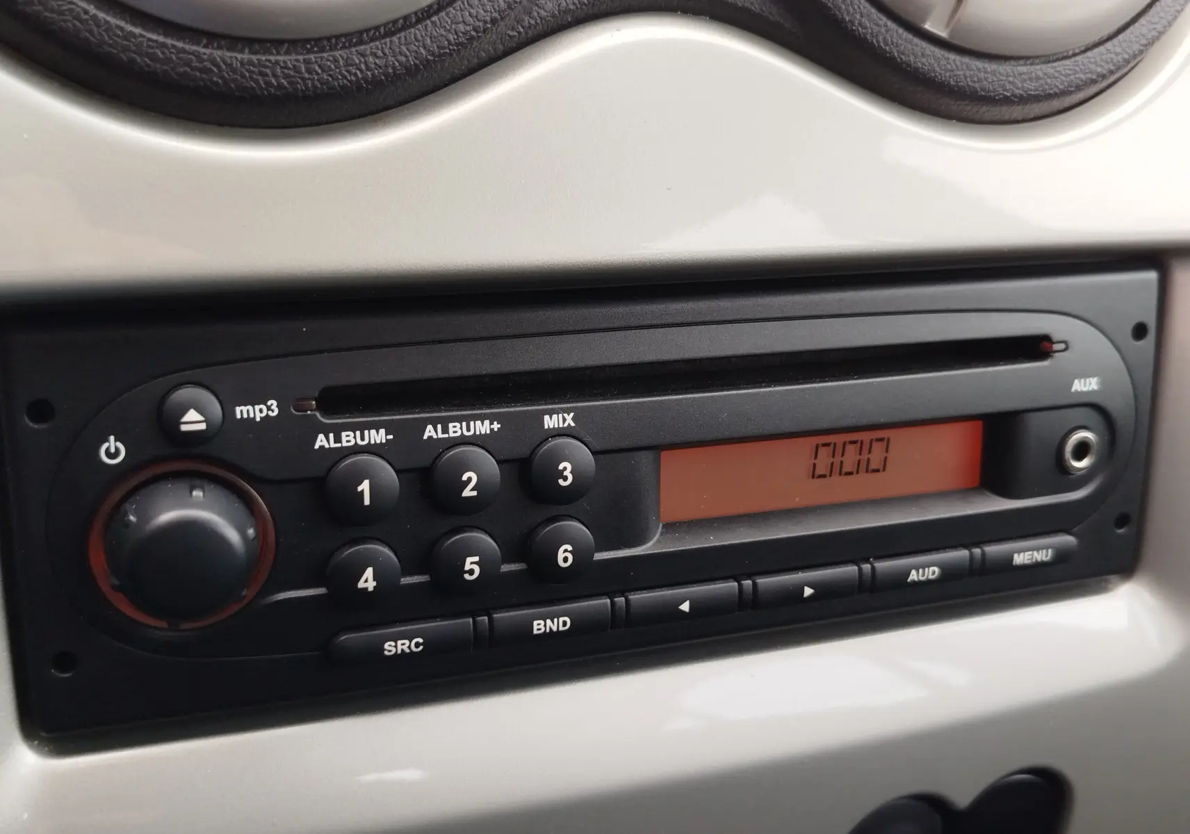 Gros plan sur la radio MP3 noire intégrée au tableau de bord gris clair de la Dacia Sandero 2011.