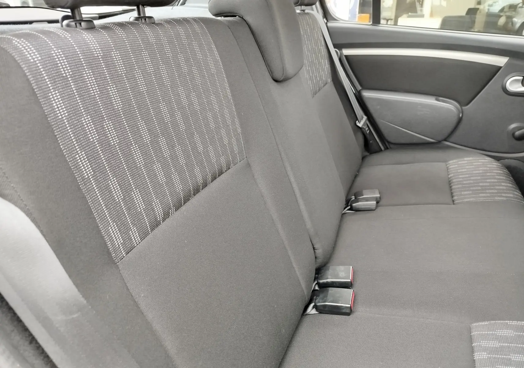 Vue latérale intérieure des sièges arrière gris tissu avec motifs, de la Dacia Sandero noire 2011, version Lauréate.