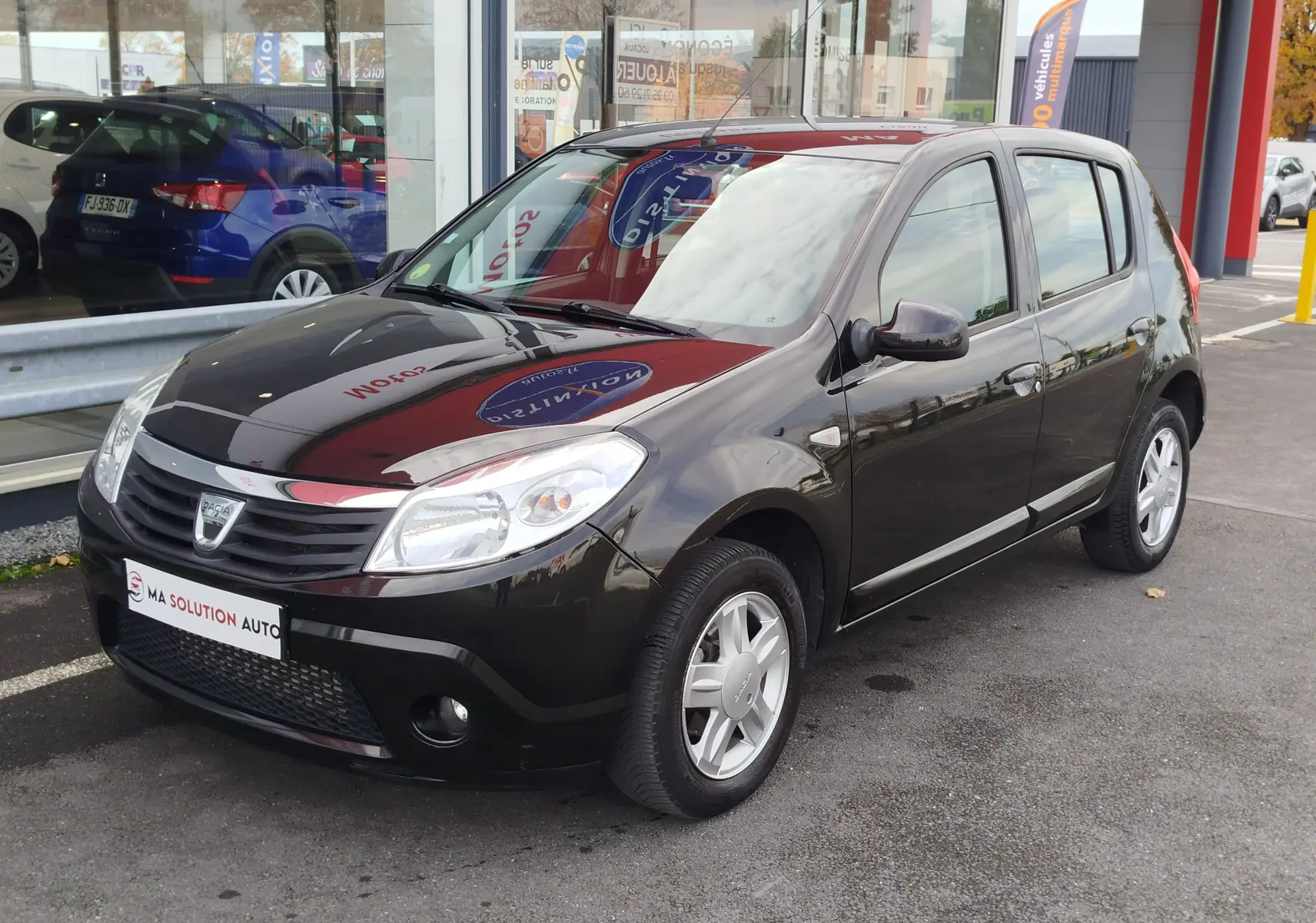 Dacia Sandero noire vue en 3/4 avant droit, avec jantes alliage et calandre distinctive au logo Dacia.