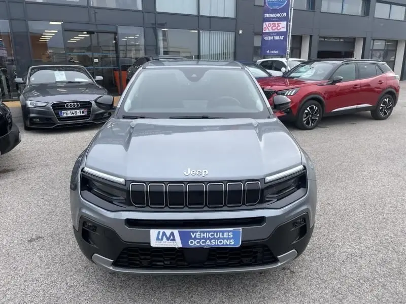 Vue de face d’un Jeep Avenger gris métal 2025 avec calandre noire distinctive et plaque « Véhicules Occasions ».