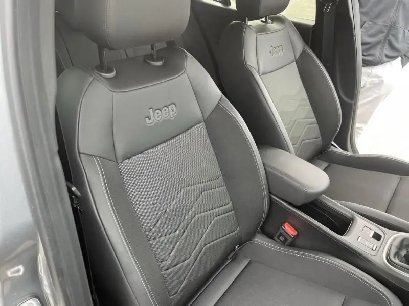 Vue intérieure rapprochée des sièges avant noirs du Jeep Avenger 2025, avec logo Jeep brodé sur les appuie-têtes.