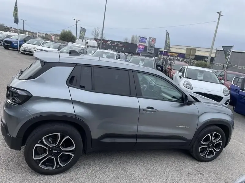 Vue latérale droite d'un Jeep Avenger gris métal 2025 avec jantes noires et toit blanc contrasté.