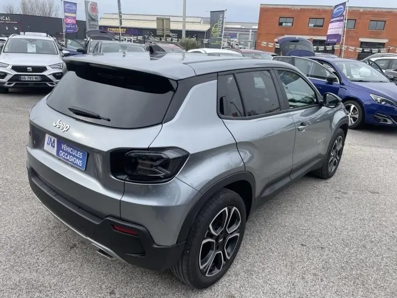 Jeep Avenger gris métal vu en 3/4 arrière droit, avec feux arrière noirs et jantes alliage distinctives.