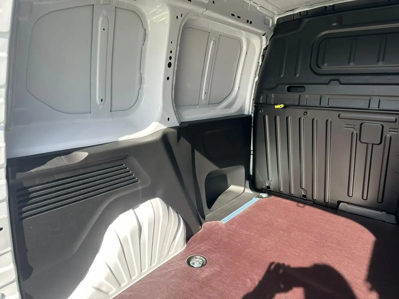 Vue intérieure de la zone de chargement arrière du Citroën Berlingo blanc Icy avec plancher bois antidérapant et parois noires.