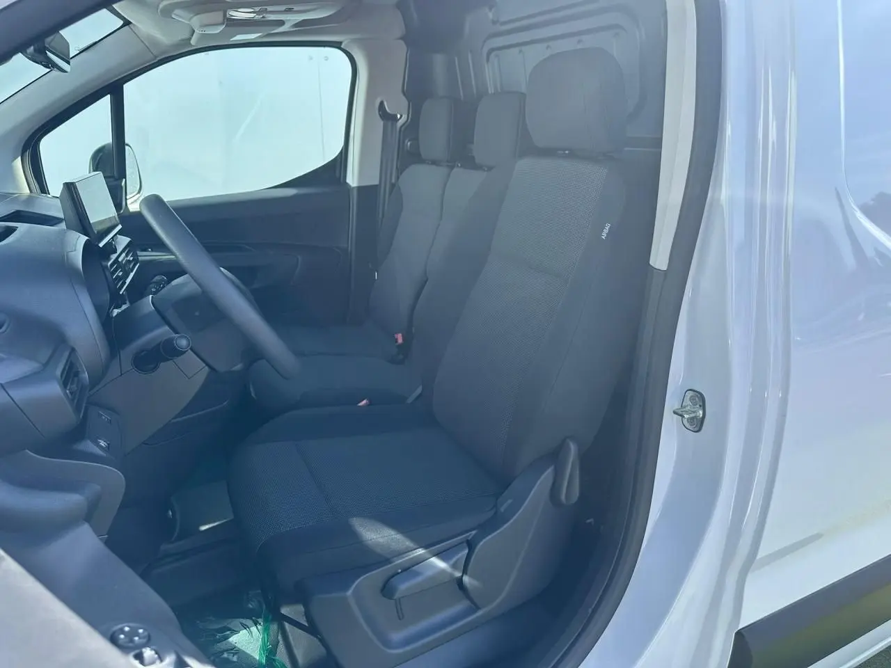 Vue intérieure côté conducteur du Citroën Berlingo blanc Icy, montrant les sièges tissu et le tableau de bord avec écran tactile.