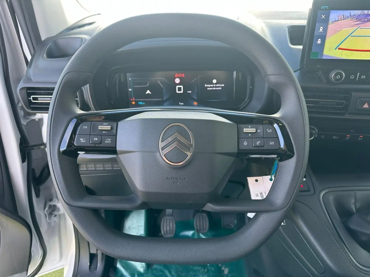 Vue intérieure centrée sur le volant multifonctions noir du Citroën Berlingo blanc avec tableau de bord numérique et écran tactile.