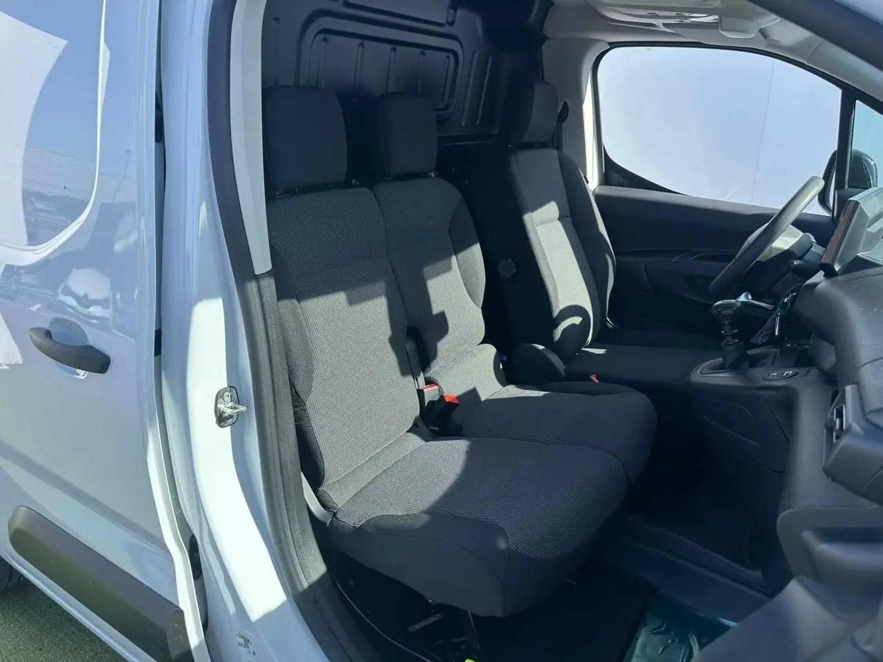 Vue intérieure côté droit du Citroën Berlingo blanc Icy, montrant les sièges avant en tissu gris et le tableau de bord.
