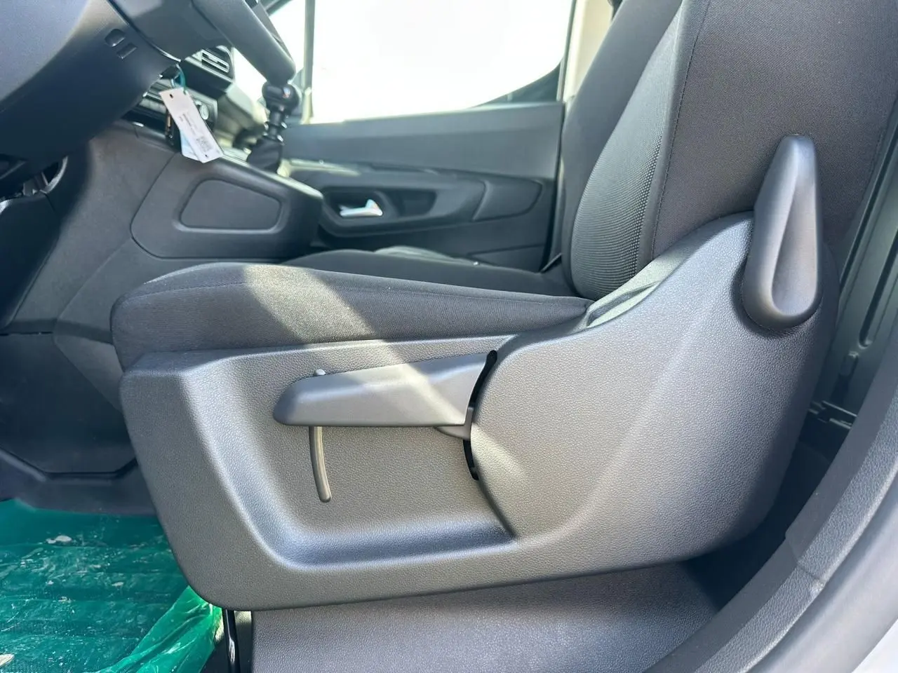 Gros plan sur le siège conducteur tissu gris côté gauche du Citroën Berlingo blanc Icy, avec levier de réglage manuel visible.
