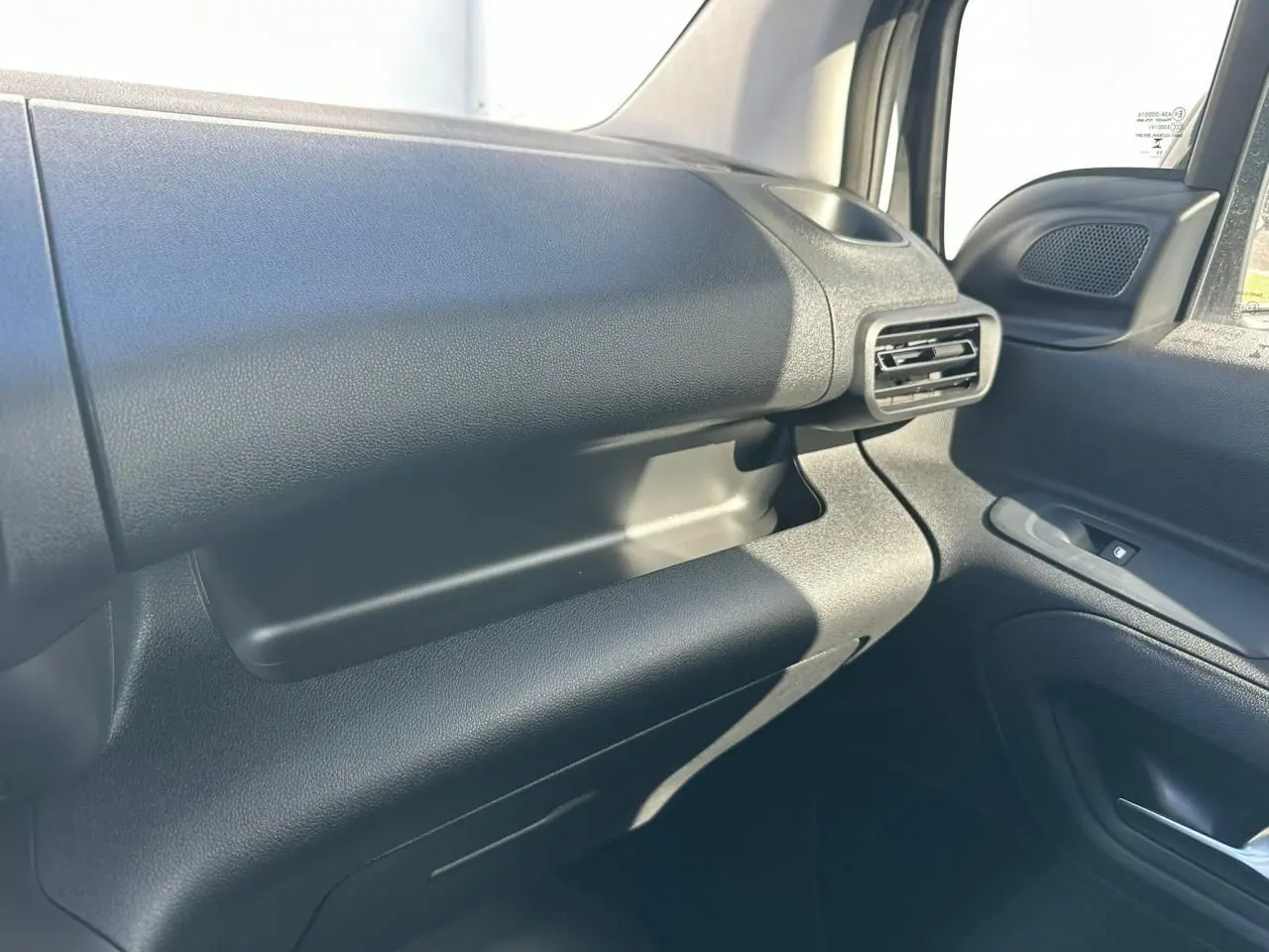 Détail de la boîte à gants fermée côté passager du Citroën Berlingo blanc Icy, vue intérieure droite.