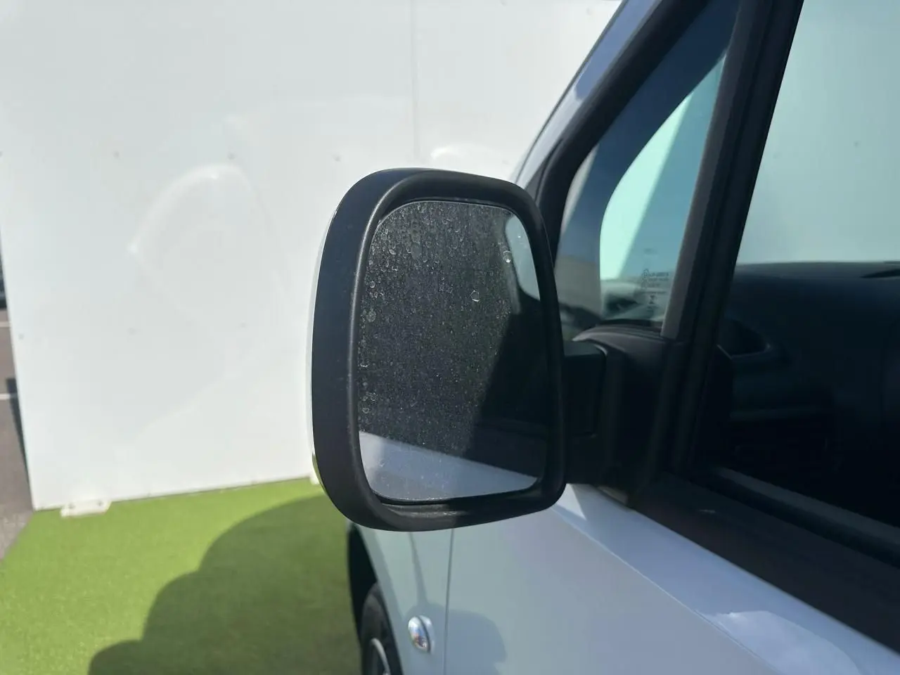 Gros plan sur le rétroviseur noir brillant côté conducteur du Citroën Berlingo blanc Icy, avec partie avant et vitre visible.