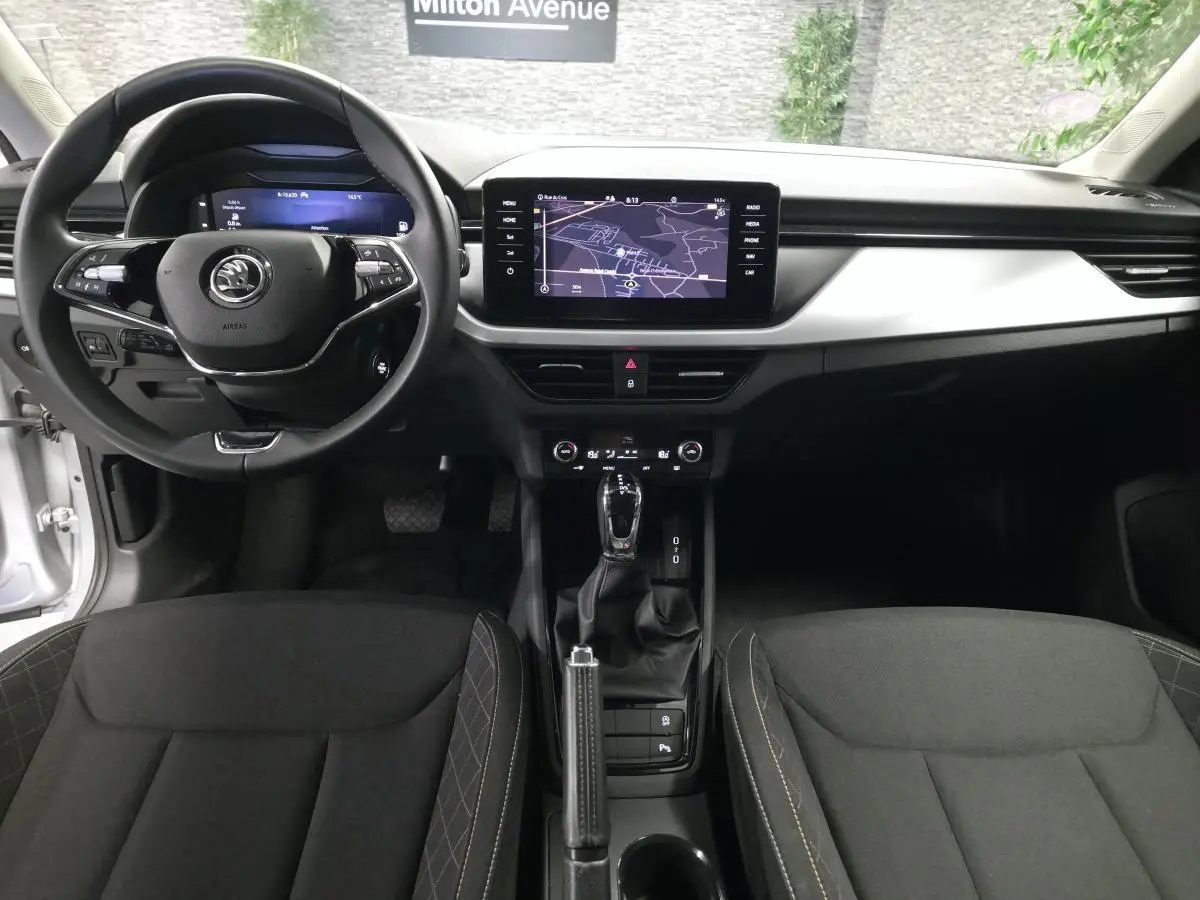 Vue intérieure avant du Skoda Kamiq 2023, tableau de bord noir avec écran tactile et volant multifonctions.