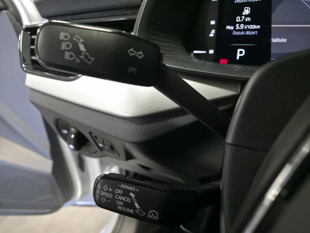 Gros plan sur les commandes au volant du Skoda Kamiq 2023 gris, avec affichage digital en arrière-plan.