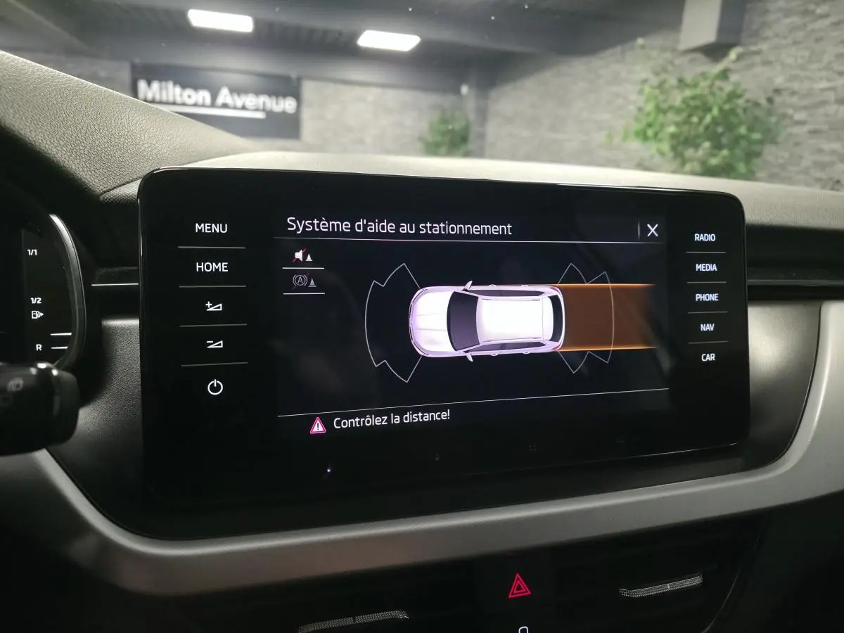 Écran tactile intérieur du Skoda Kamiq 2023 montrant l’aide au stationnement avec alertes de distance.