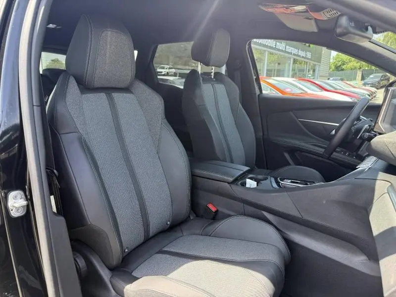 Vue intérieure côté conducteur du Peugeot 3008 Hybride Rechargeable 2024, sièges tissu et cuir gris, tableau de bord moderne.