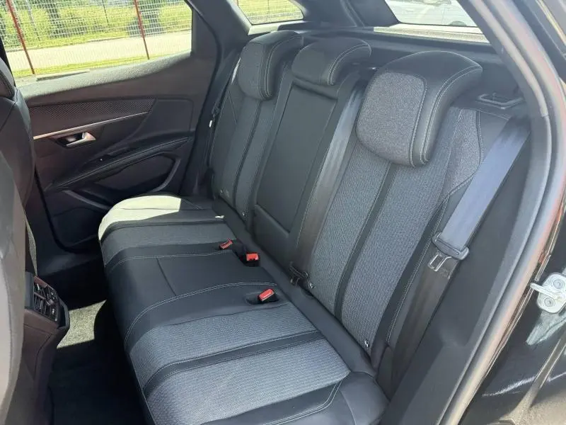 Vue intérieure côté droit des sièges arrière en tissu et cuir noir du Peugeot 3008 Hybride Rechargeable 2024, avec ceintures de sécurité visibles.