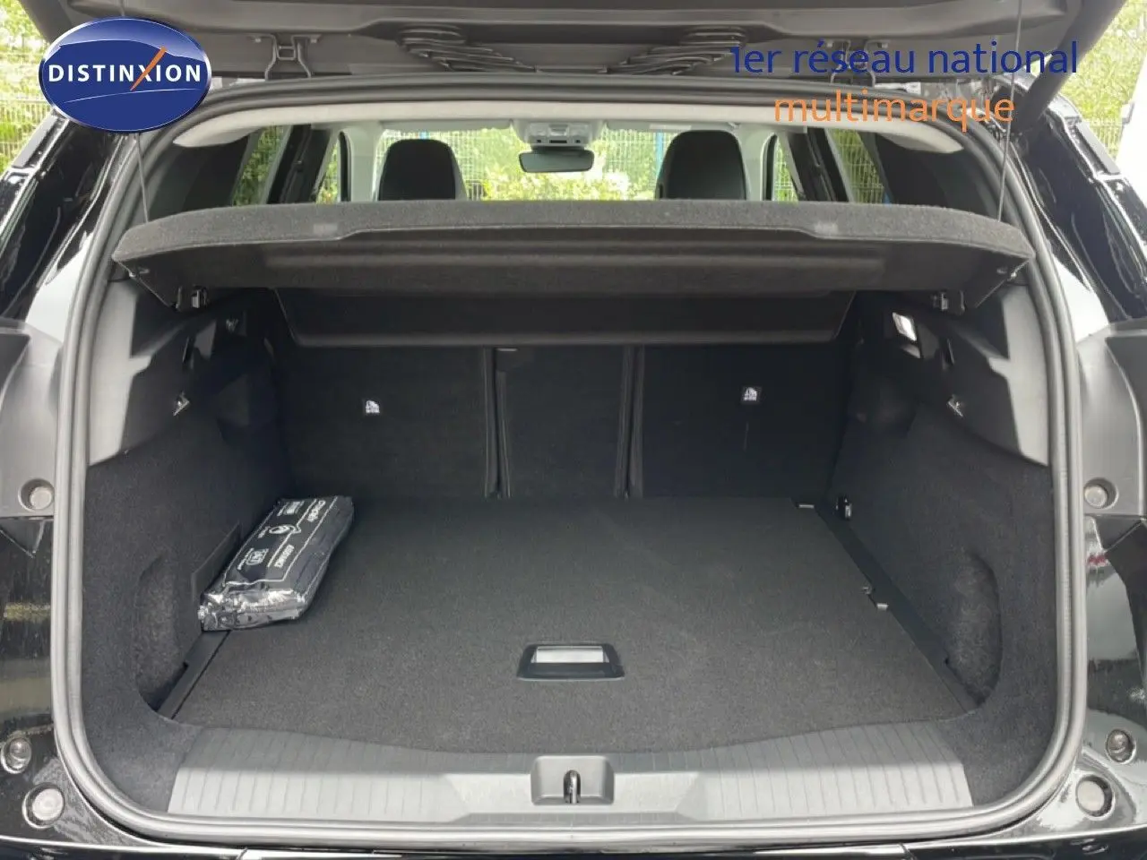 Coffre ouvert d’un Citroën C5 Aircross Hybrid noir perle métal, vue arrière montrant l’espace de chargement et la tablette cache-bagages.